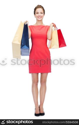 shopping, sale, christmas and holiday concept - smiling elegant woman in red dress with shopping bags