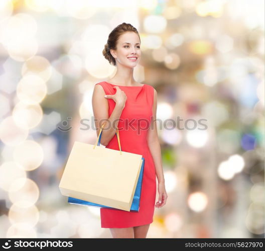 shopping, sale, christmas and holiday concept - smiling elegant woman in red dress with shopping bags