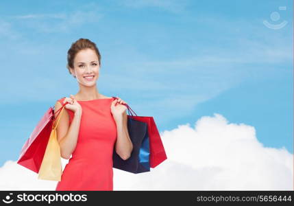 shopping, sale, christmas and holiday concept - smiling elegant woman in red dress with shopping bags