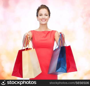 shopping, sale, christmas and holiday concept - smiling elegant woman in red dress with shopping bags