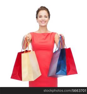 shopping, sale, christmas and holiday concept - smiling elegant woman in red dress with shopping bags