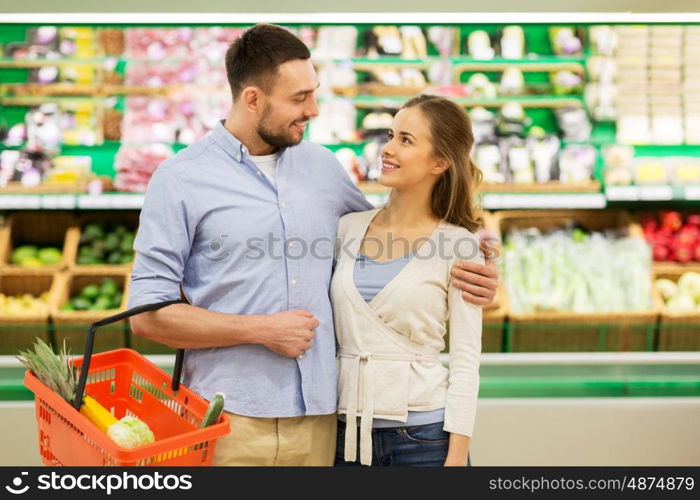 shopping, sale, consumerism and people concept - happy couple with food basket at grocery store or supermarket