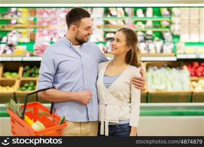 shopping, sale, consumerism and people concept - happy couple with food basket at grocery store or supermarket