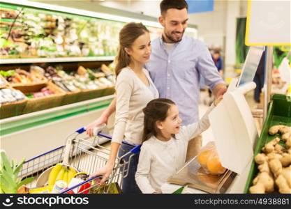 shopping, sale, consumerism and people concept - happy family with child weighing oranges on scale at grocery store. family weighing oranges on scale at grocery store