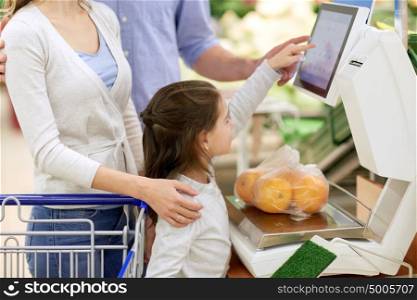 shopping, sale, consumerism and people concept - happy family with child weighing oranges on scale at grocery store. family weighing oranges on scale at grocery store