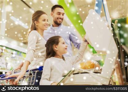 shopping, sale, consumerism and people concept - happy family with child weighing oranges on scale at grocery store or supermarket over snow. family weighing oranges on scale at grocery store