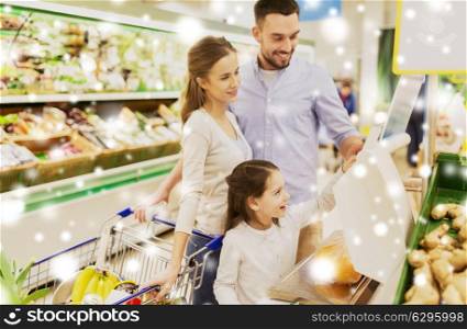 shopping, sale, consumerism and people concept - happy family with child weighing oranges on scale at grocery store or supermarket over snow. family weighing oranges on scale at grocery store