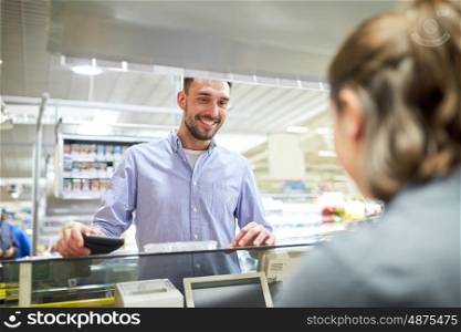 shopping, sale, consumerism and people concept - happy man with wallet at grocery store or supermarket cash register
