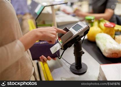 shopping, sale, consumerism and people concept - woman buying food at grocery store or supermarket cash register and entering pin code. woman entering pin code at store cash register