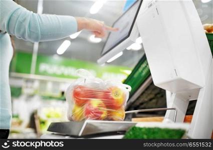shopping, sale, consumerism and people concept - woman weighing apples on scale at grocery store. woman weighing apples on scale at grocery store. woman weighing apples on scale at grocery store