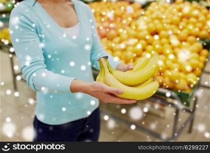 shopping, sale, food, consumerism and people concept - female customer with bananas at grocery store over snow. customer with bananas at grocery store