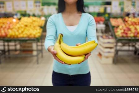 shopping, sale, food, consumerism and people concept - happy woman with bananas at grocery store