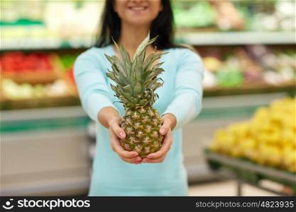 shopping, sale, food, consumerism and people concept - happy woman with pineapple at grocery store