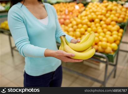 shopping, sale, food, consumerism and people concept - woman with bananas at grocery store