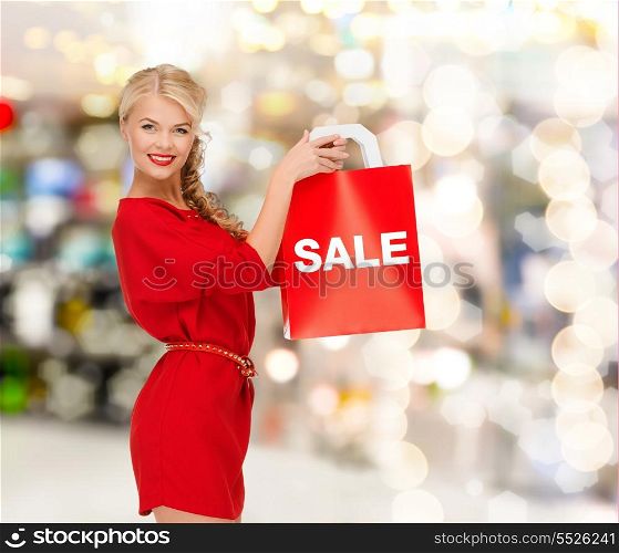 shopping, sale, gifts, christmas and mall concept - smiling woman in red dress with shopping bags at shopping mall