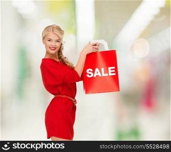 shopping, sale, gifts, christmas and mall concept - smiling woman in red dress with shopping bags at shopping mall