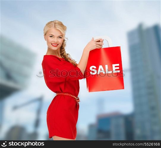 shopping, sale, gifts, christmas and x-mas concept - smiling woman in red dress with shopping bags outdoors