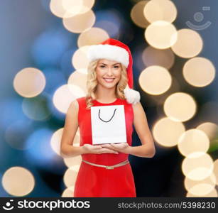shopping, sale, gifts, christmas, x-mas concept - smiling woman in red dress and santa helper hat with shopping bag