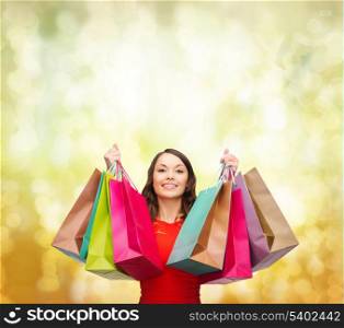 shopping, sale, gifts, christmas, x-mas concept - smiling woman in red dress with colorful shopping bags