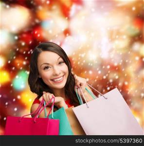shopping, sale, gifts, christmas, x-mas concept - smiling woman in red dress with shopping bags