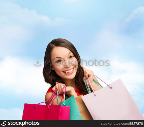 shopping, sale, gifts, christmas, x-mas concept - smiling woman in red dress with shopping bags