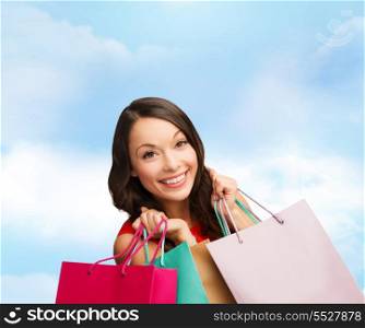 shopping, sale, gifts, christmas, x-mas concept - smiling woman in red dress with shopping bags