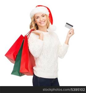 shopping, sale, gifts, christmas, x-mas concept - smiling woman in santa helper hat with shopping bags and credit card