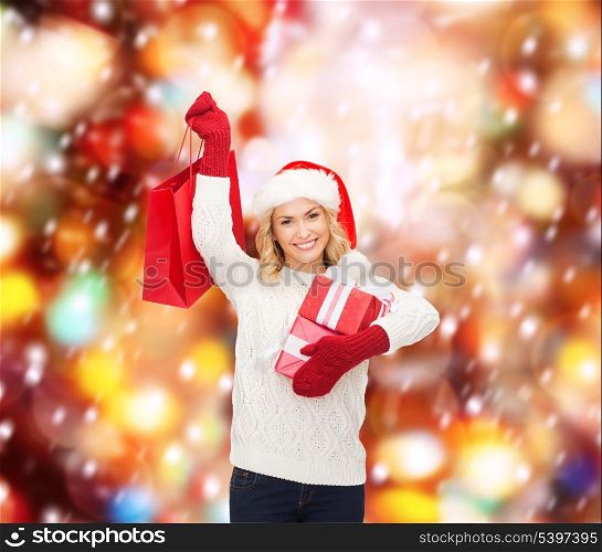 shopping, sale, gifts, christmas, x-mas concept - smiling woman in santa helper hat with shopping bags and gift boxes