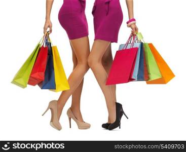 shopping, sale, gifts concept - two women in pink dresses with shopping bags