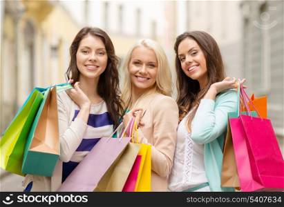 shopping, sale, happy people and tourism concept - beautiful girls with shopping bags in ctiy