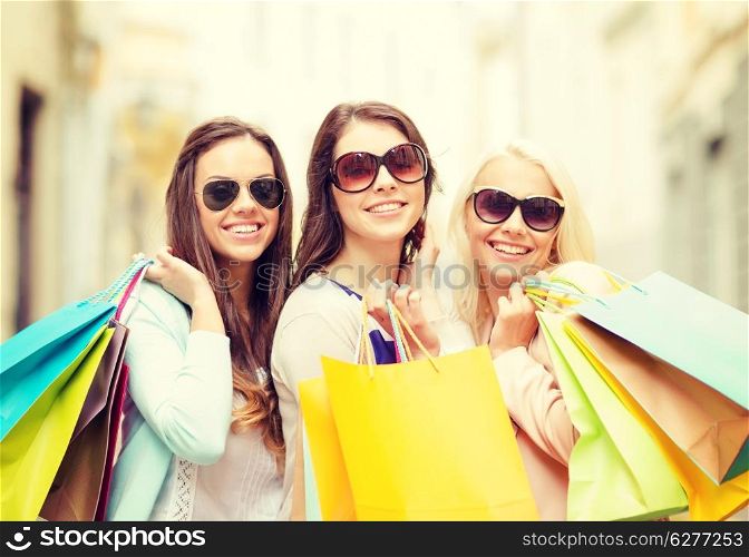 shopping, sale, happy people and tourism concept - three beautiful girls in sunglasses with shopping bags in ctiy