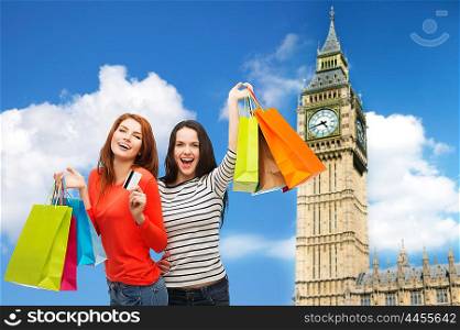 shopping, sale, tourism and people concept - two smiling teenage girls with shopping bags and credit card over big ben clock tower background