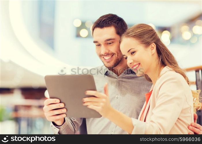 shopping, technology and people concept - happy couple with tablet pc taking selfie in mall or business center