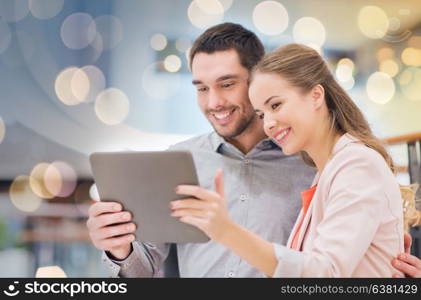 shopping, technology and people concept - happy couple with tablet pc taking selfie in mall or business center. happy couple with tablet pc taking selfie in mall