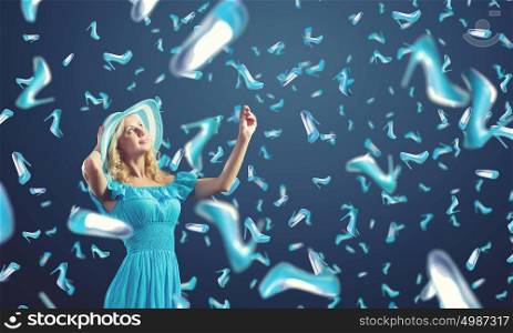 Shopping therapy. Young cheerful woman in blue dress and many falling shoes