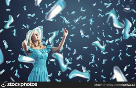 Shopping therapy. Young cheerful woman in blue dress and many falling shoes