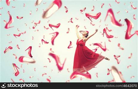 Shopping therapy. Young cheerful woman in dress and many falling shoes