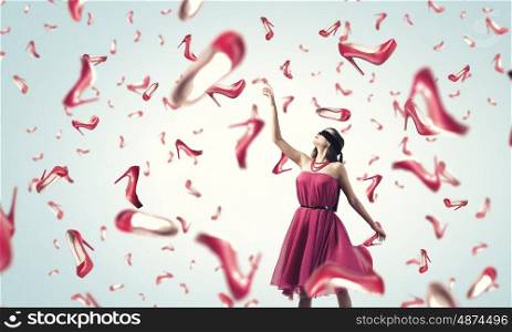 Shopping therapy. Young woman in dress and many falling shoes