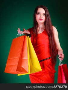 Shopping time and sale concept. Young woman holding bags in hands on green background in studio.