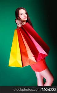 Shopping time and sale concept. Young woman holding bags in hands on green background in studio.