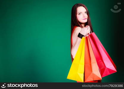 Shopping time and sale concept. Young woman holding bags in hands on green background in studio.