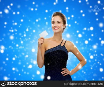 shopping, wealth, holidays and people concept - smiling woman in evening dress holding credit card over blue snowy background