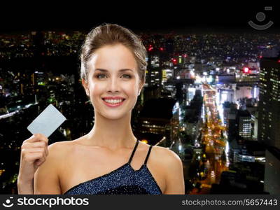 shopping, wealth, money, luxury and people concept - smiling woman in evening dress holding credit card over night city background