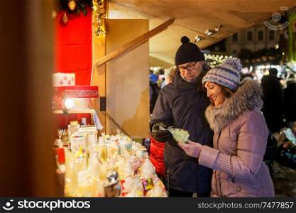 shopping, winter holidays and people concept - happy senior couple at christmas market souvenir shop stall on town hall square in tallinn, estonia. happy senior couple hugging at christmas market