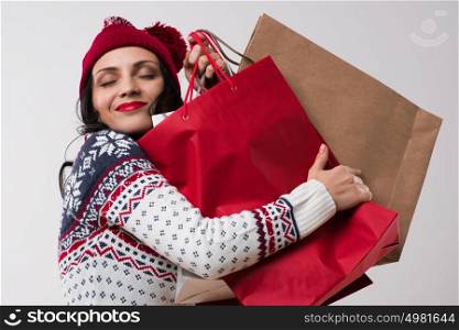 Shopping winter woman embracing shopping bags with eyes closed on white background.