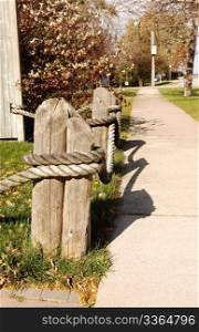 Short but big fence posts on a walkway with big ropes around, in brightsunshine.