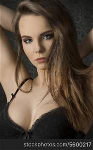 Short portrait of beautiful, young, sensual woman with long, straight, brown hair, dark make up, wearing sexy, balck lingerie, lookong at the camera.