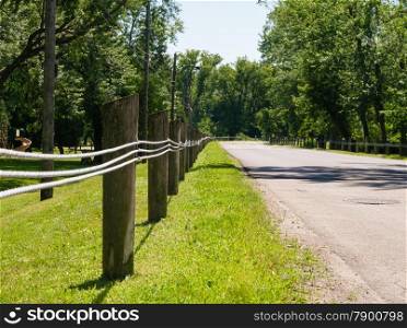 Short wooden fence posts with steel lines along empty street.