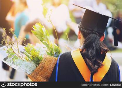 shot back side young female student in hand holding a bouquet of flowers the graduates of graduation hats during commencement success graduates of the university, Concept education congratulation.