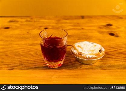 Shot glass with slow gin and mince pie, on wooden table.